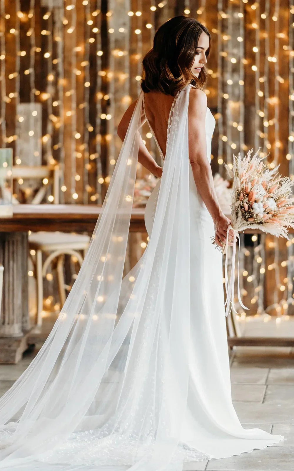 Vestido de novia sencillo de corte trompeta con escote en V, sin mangas, largo hasta el suelo y cola larga en la espalda en V.